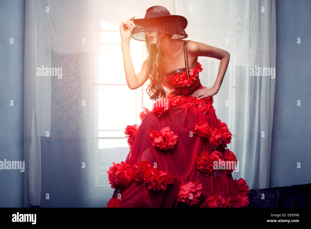 La donna in un abito rosso in piedi nella parte anteriore della finestra Foto Stock