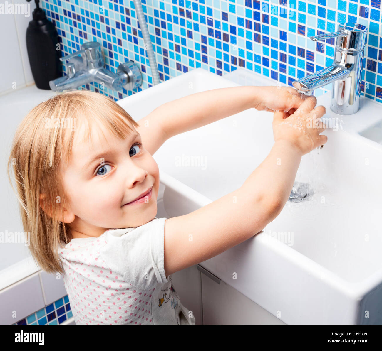Bambina lavando le mani nel lavandino del bagno Foto Stock
