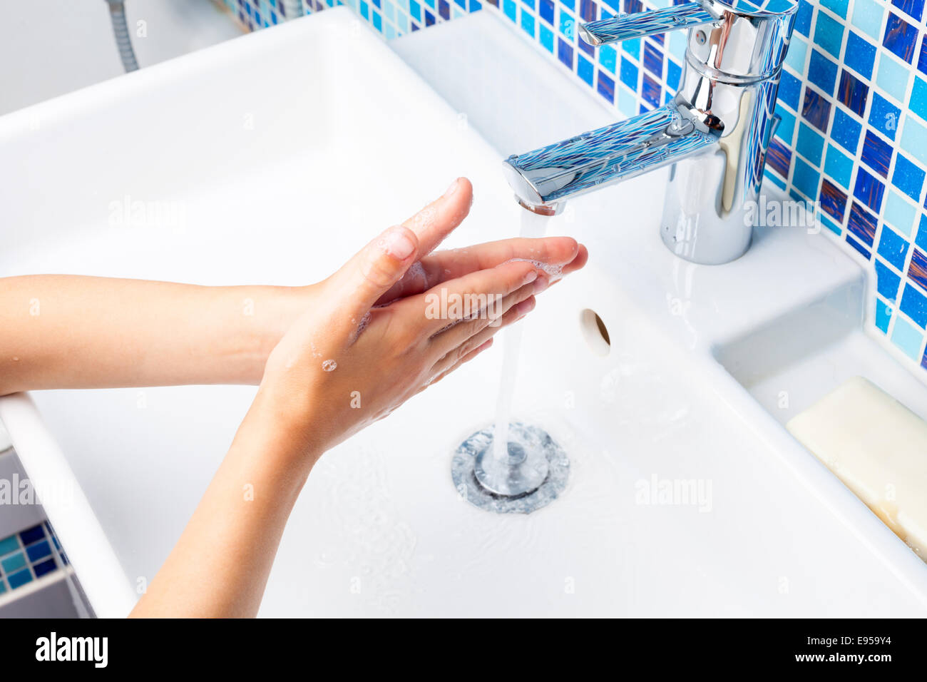 Ragazza lavando le mani con sapone in un lavandino del bagno Foto Stock
