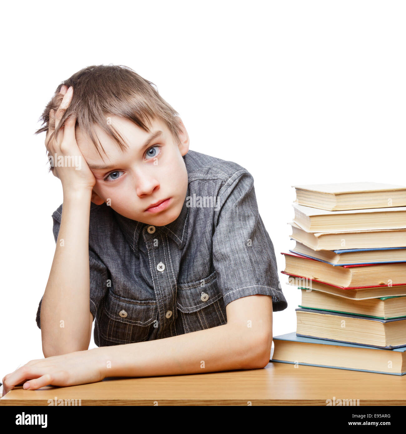 Ritratto di sconvolgere schoolboy seduto alla scrivania con libri tenendo la sua testa Foto Stock