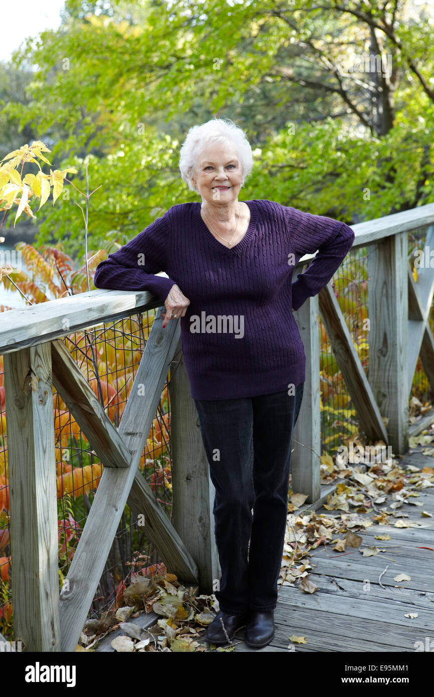 85 anno vecchia donna in piedi sulla rampa del dock nel paesaggio autunnale. Foto Stock