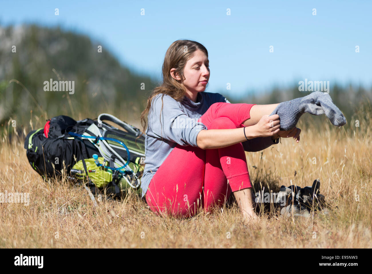 Donna mettendo su calze su uno zaino viaggio in Oregon Wallowa della montagna. Foto Stock