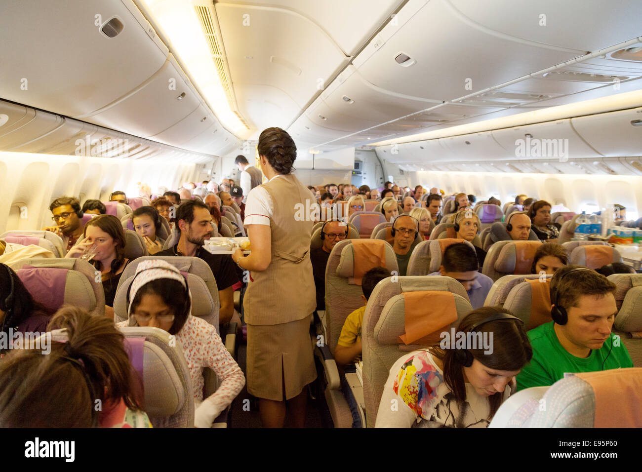 Passeggeri e hostess a bordo di una compagnia aerea Emirates piano; la cabina di un Boeing 777 volo da Londra a Dubai Foto Stock