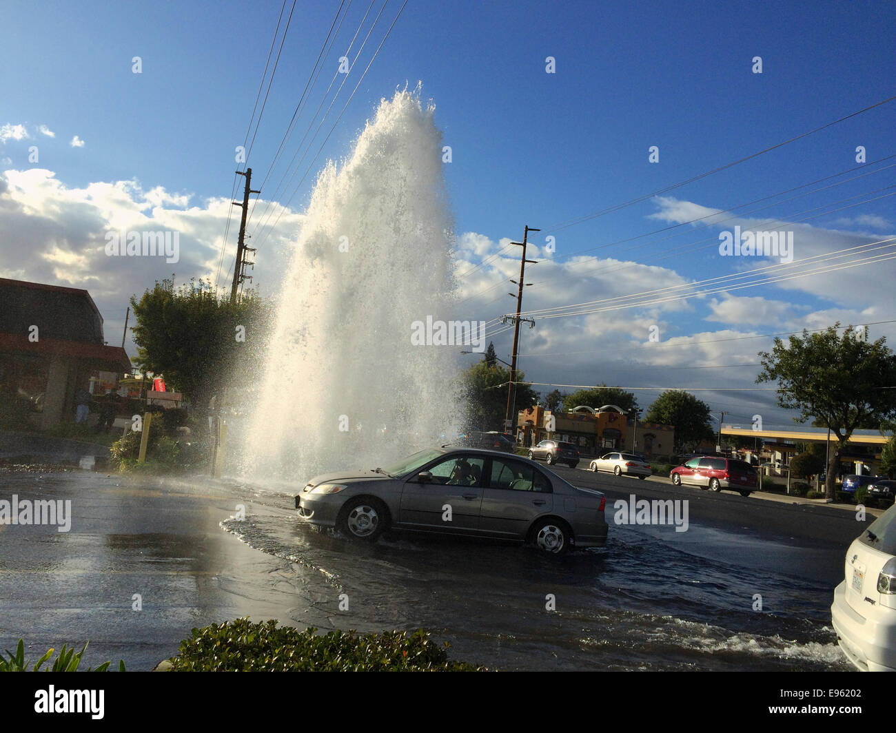 Modesto, California, USA. Ottobre 20, 2014. Un solo incidente di auto su Standiford Ave vicino Tully provoca inondazioni di questo pomeriggio dopo che il conducente virato nell'idrante di fuoco nella parte anteriore del Tully Manor Shopping Center. Un modesto operaio della città è stato veloce a rispondere girando l'acqua. Vi è una grave siccità in California. Credito: Don Bartell / Alamy Live News Foto Stock