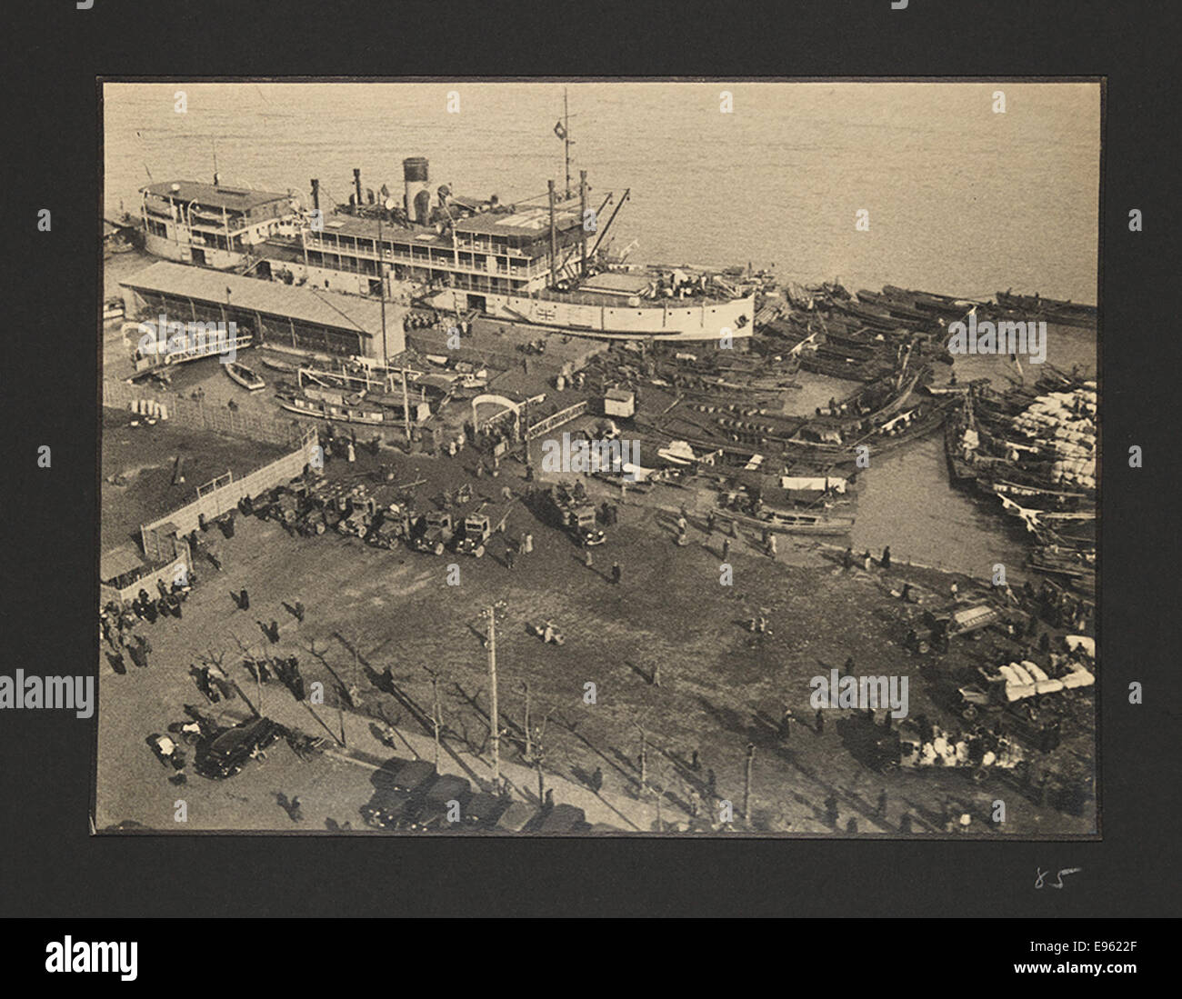 Una fotografia di una nave britannica attraccata accanto ai sampan, piccole imbarcazioni comunemente usate nei porti asiatici. L'immagine proviene dalla guerra sino-giapponese (1937-1945), che mostra la scena marittima durante la guerra. Foto Stock