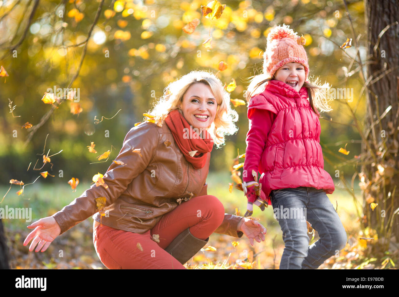 Felice genitore e bambino outdoor giocare con l'autunno foglie gialle Foto Stock