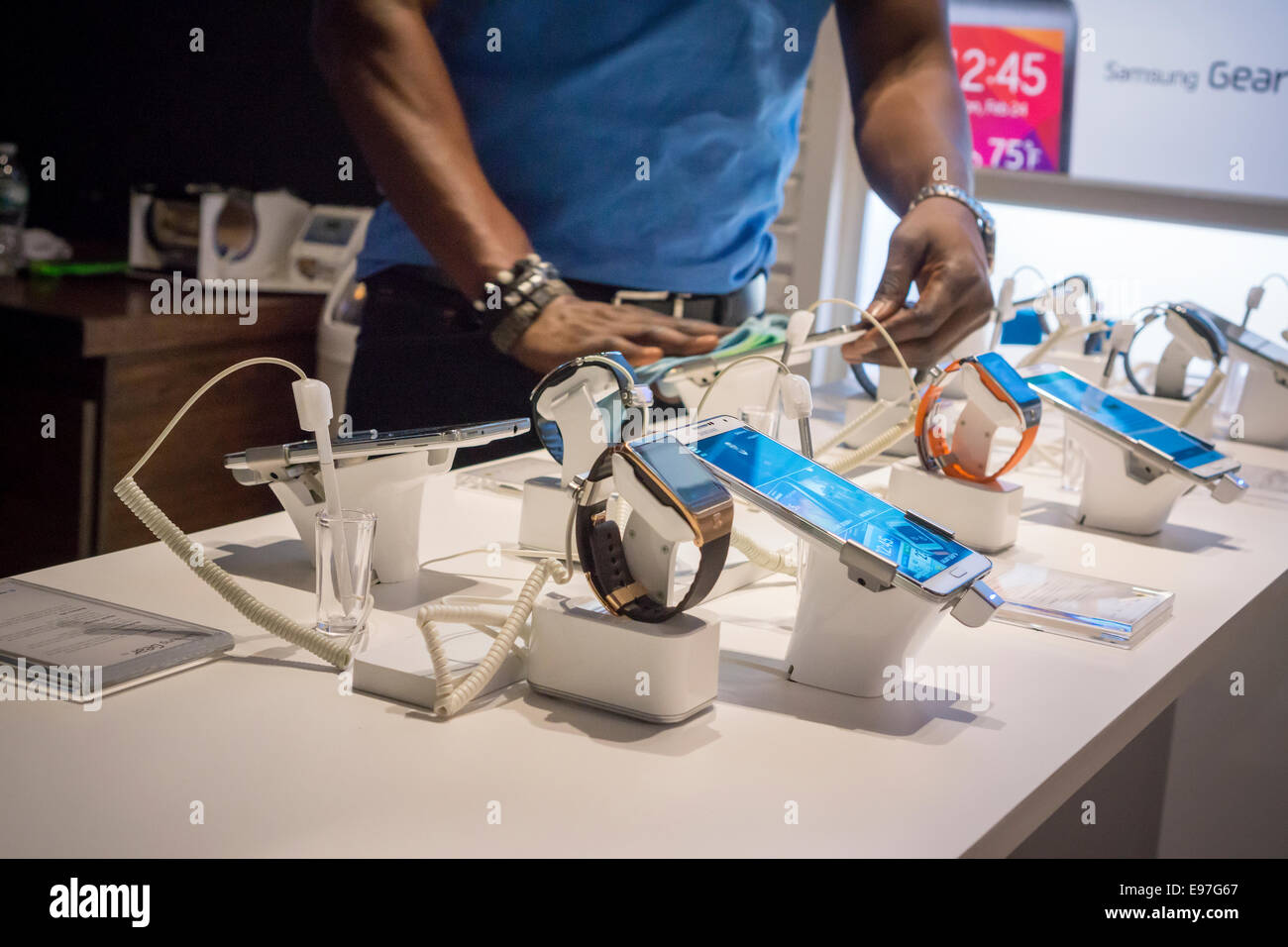 Un lavoratore pulisce unto i segni delle dita al di fuori della i prodotti Samsung in un Samsung pop-up shop a Soho a New York Foto Stock