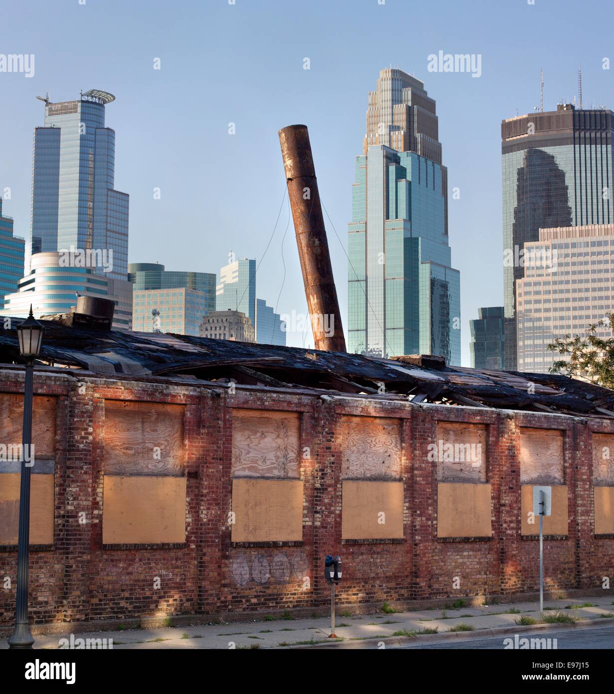 Il vecchio edificio di mattoni con fumaiolo pendente nello storico quartiere di magazzino con i grattacieli del centro di Minneapolis, MN, Stati Uniti d'America Foto Stock