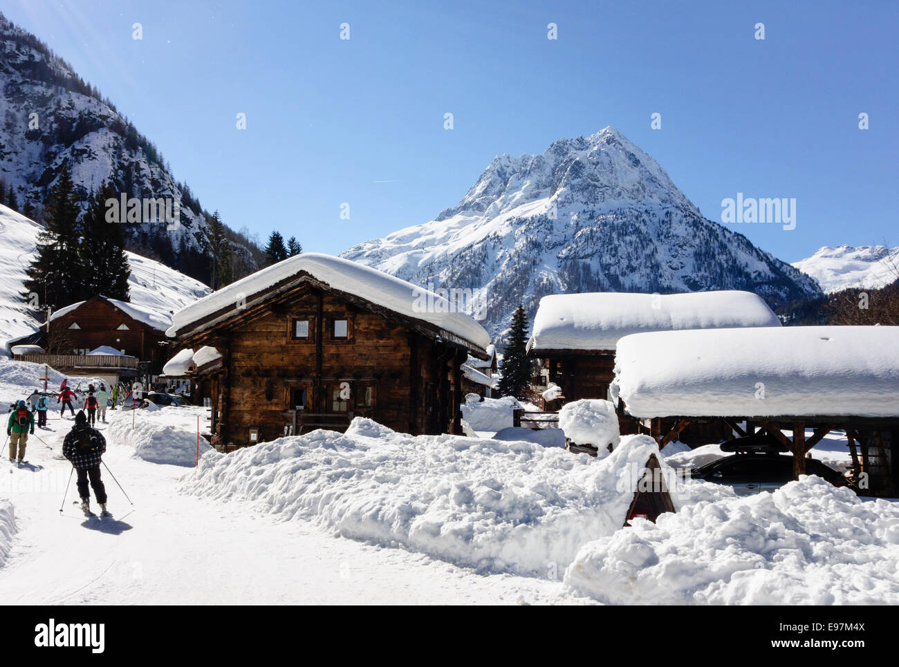 Sciatori sul pendio di neve avvicinando piccolo villaggio alpino resort di Vallorcine nella valle di Chamonix, Haute Savoie, Rhone-Alpes, Francia Foto Stock