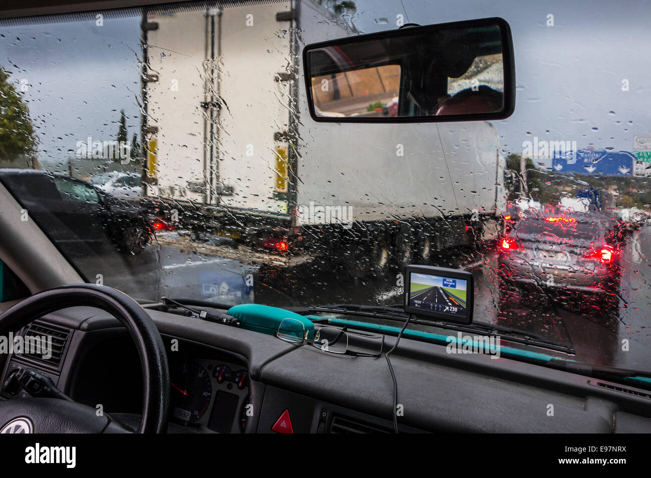 Carrello il sorpasso di vetture su autostrada durante heavy rain shower visto dall'interno del veicolo con grosse gocce di pioggia sul parabrezza Foto Stock