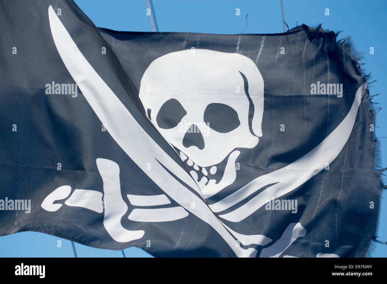 Il Jolly Roger cranio e spade Pirate bandiera blu su sfondo cielo Foto Stock