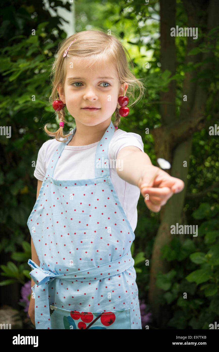 Bambina con ciliegie penzolante dal suo orecchio Foto Stock