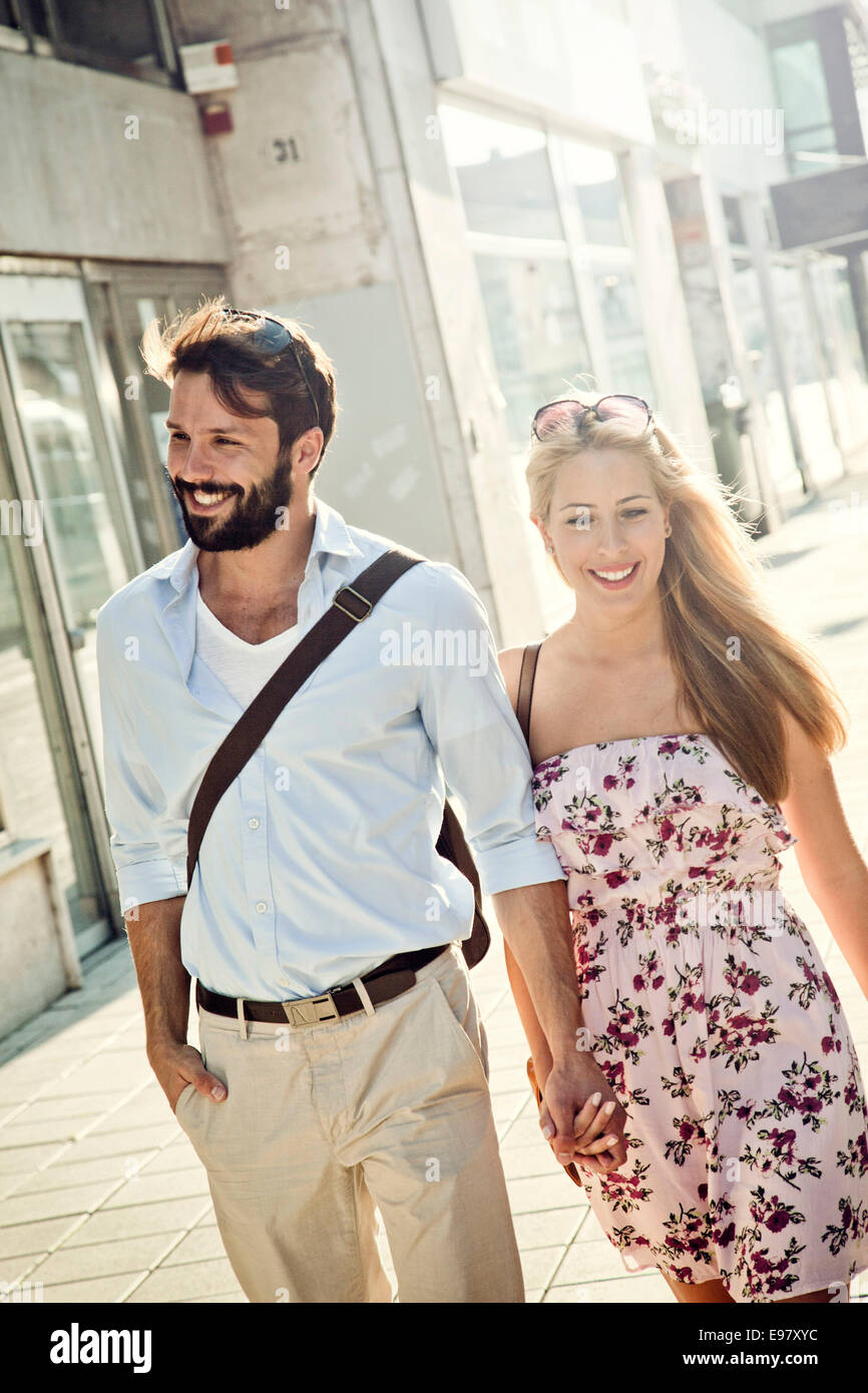 Felice coppia giovane passeggiate in città tenendo le mani Foto Stock