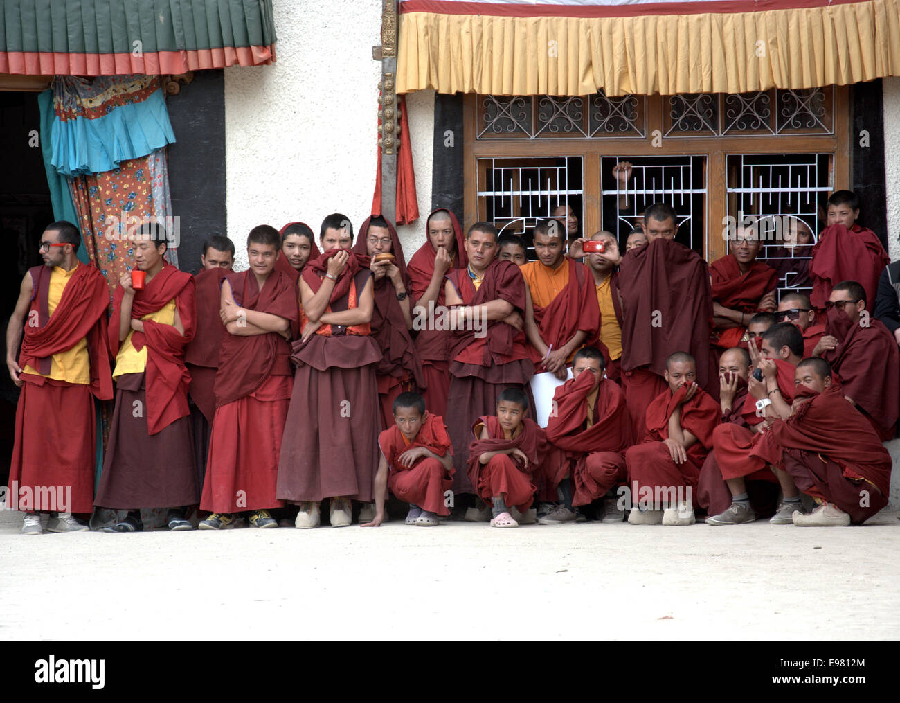 Artisti mascherati mettono in scena la parte teatrale di un rituale di danza Cham, osservato da attenti monaci buddisti in un monastero Ladakhi. Foto Stock