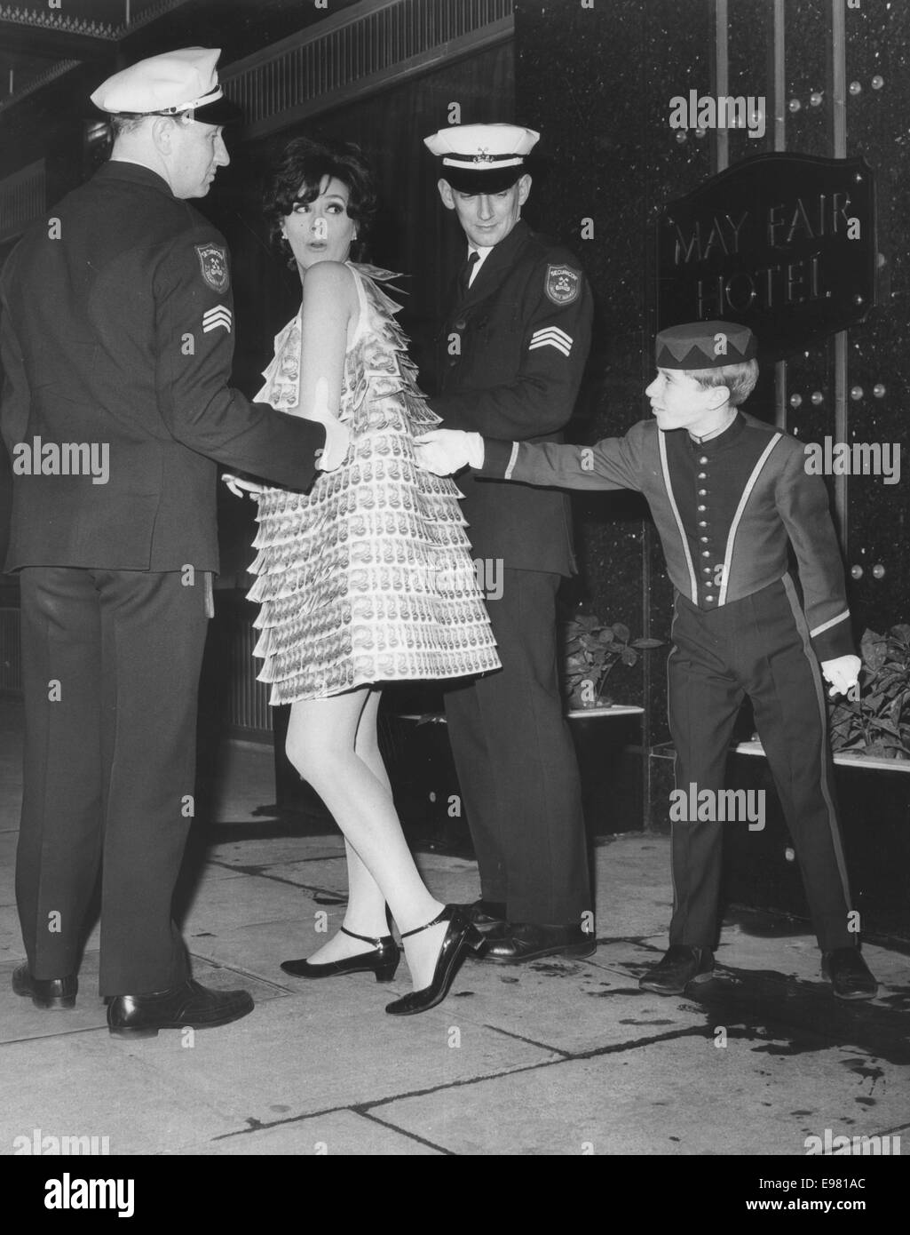 Londra, UK, UK. 2° febbraio 1967. Ex modello, girato attrice Sue LLOYD, indossando un abito realizzato da 1.000 bps e scortato da guardie di sicurezza, sguardi torna come pageboy PIETRO OVETT, 16, cerca di strappare una libbra nota, mentre Lloyd fa il suo modo di Miss Mayfair 1967 lancio champagne party tenuto presso il Mayfair Hotel. L evento è stato gestito dalla British Man's magazine Mayfair per trovare la ragazza più bella in Gran Bretagna. © Keystone foto/ZUMA filo/ZUMAPRESS.com/Alamy Live News Foto Stock