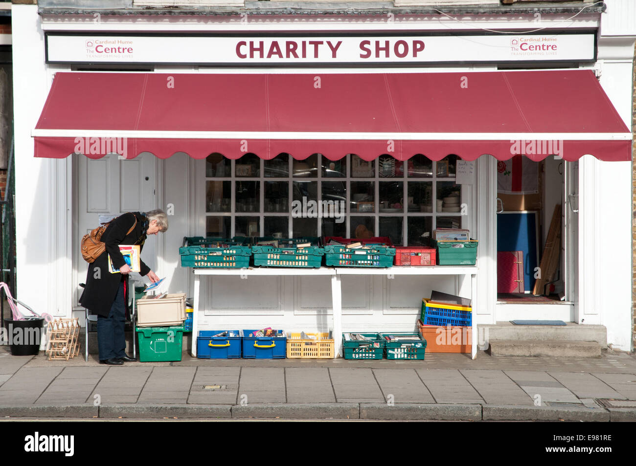 Donna navigando in un negozio di carità, London, England, Regno Unito Foto Stock