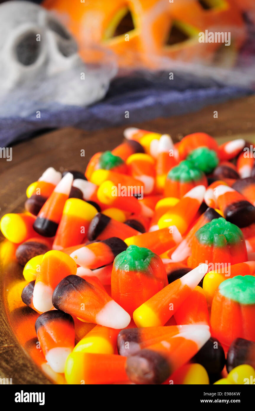 Un mucchio di diverse caramelle di Halloween con ornamenti spaventoso in background, come teschi e ragnatele e zucche Foto Stock