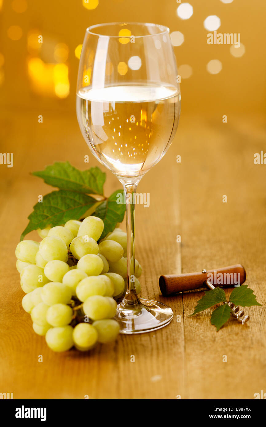 Bicchiere di vino bianco e uva con un cavatappi contro una festosa bokeh di luci di partito Foto Stock