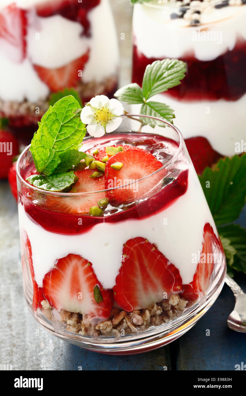 Fragola budino di crema dessert con cereali e yogurt su un blu sullo sfondo di legno per la primavera concetti alimentari Foto Stock