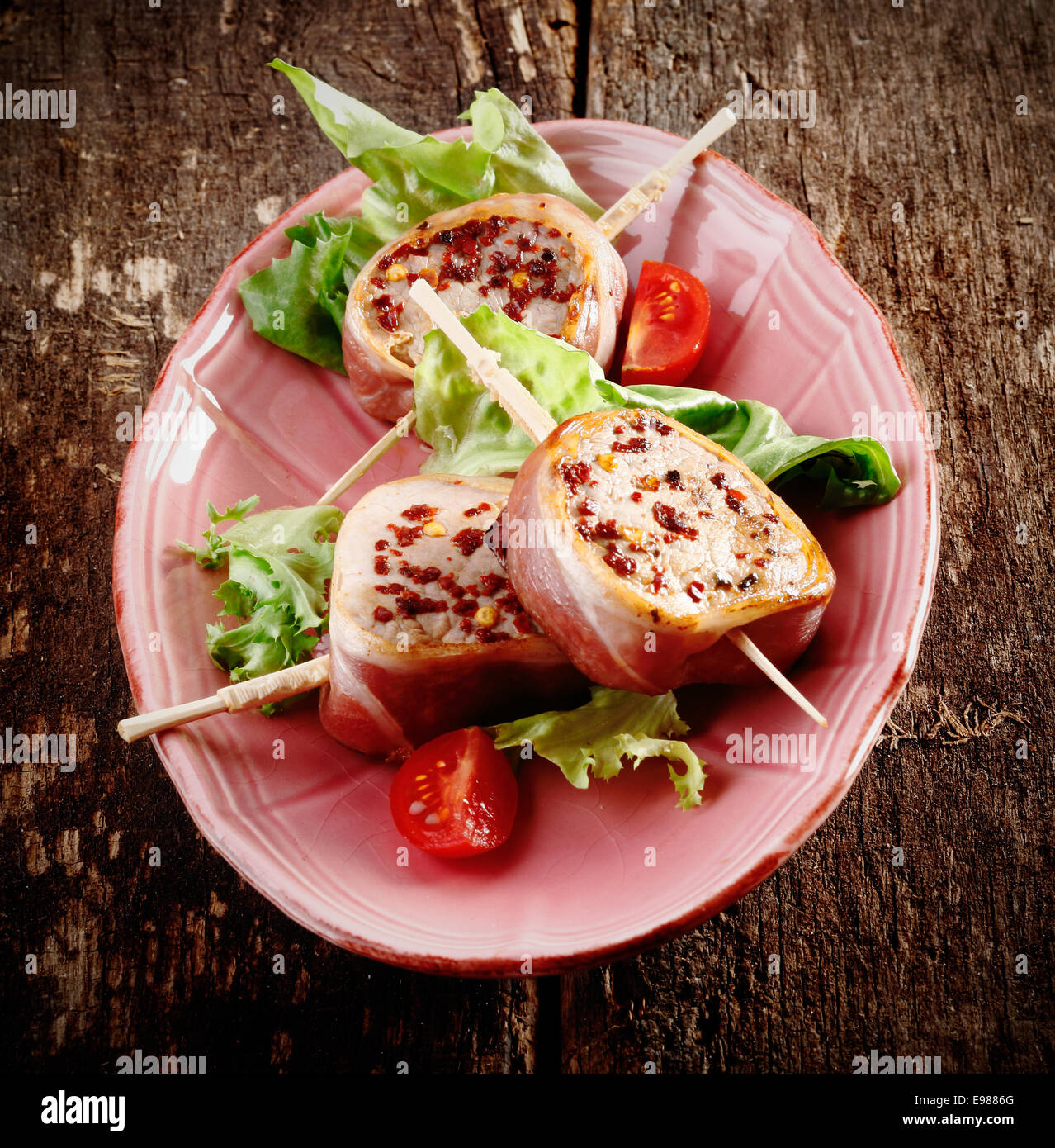 Rustico di Filetto di Maiale con Insalata di pomodoro servita su una vecchia tavola di legno Foto Stock