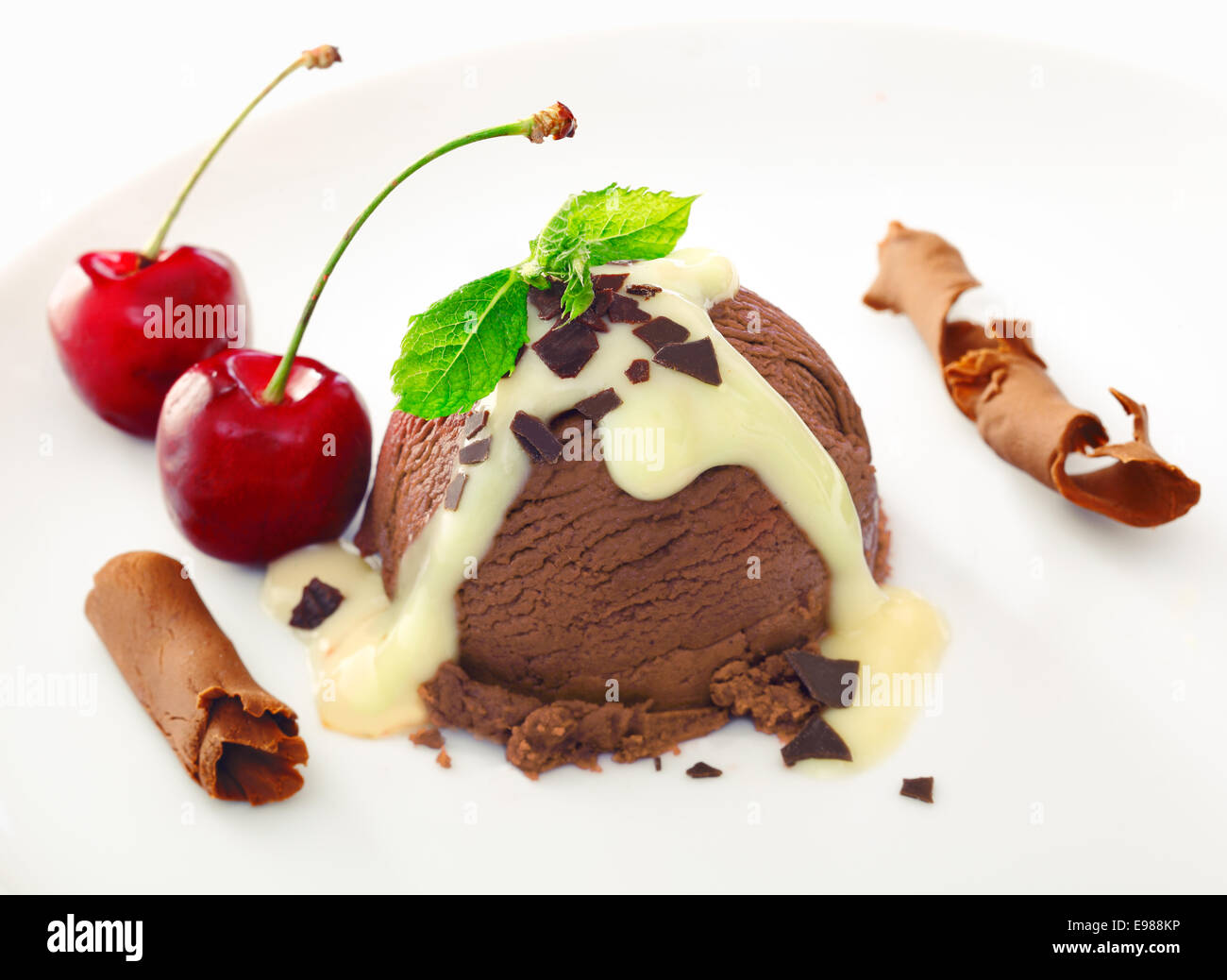 Delizioso cioccolato ricco gelato dessert spruzzata con la salsa e servite con maturi ciliege rosse e avvolto scaglie di cioccolato al latte Foto Stock