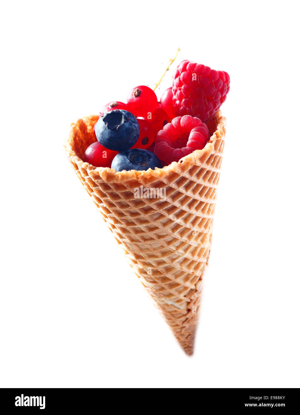 Cono gelato riempito con freschi mirtilli, lamponi e ribes rosso isolato su sfondo bianco. Foto Stock