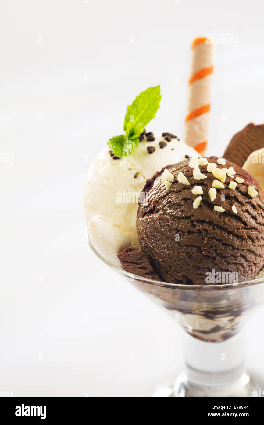 Palline di cioccolato e con gelato alla vaniglia e rabboccato con noci tritate in una conica parfait di vetro piatto Foto Stock