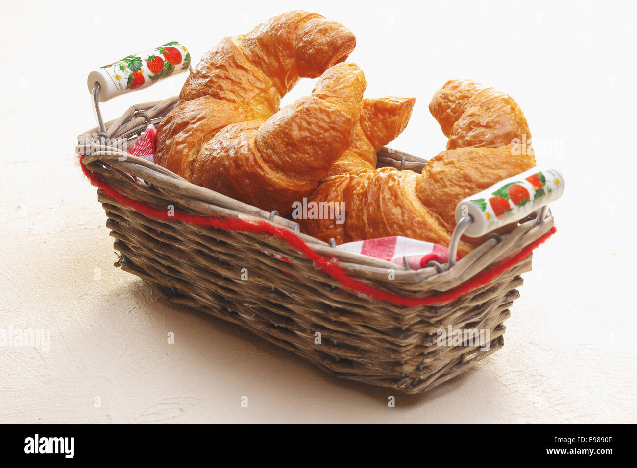 Cesto di pane appena sfornato golden a mezzaluna croissant su un piano portapaziente bianco per servire come accompagnamento per un pasto Foto Stock