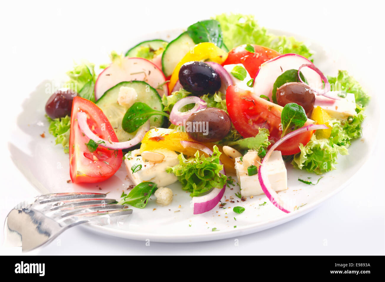 Una sana insalata greca per il pranzo con nitide foglie verdi, olive, feta, cipolla, pomodoro, cetriolo e ravanelli su sfondo bianco Foto Stock