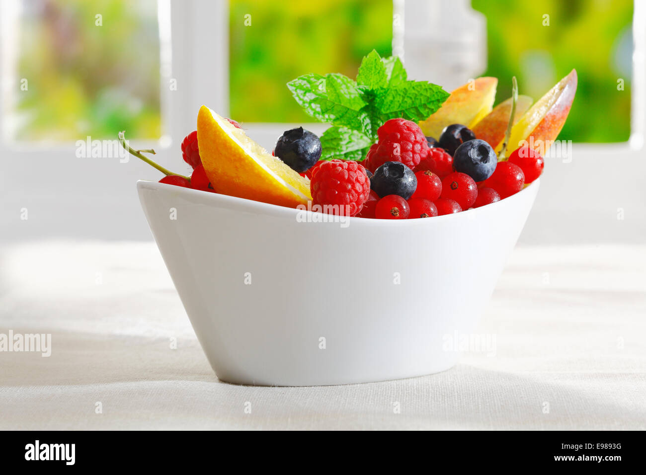 Esotico dessert di frutta in una barca di decorazione a forma di ciotola con fette di arancia e un assortimento di bacche mature Foto Stock