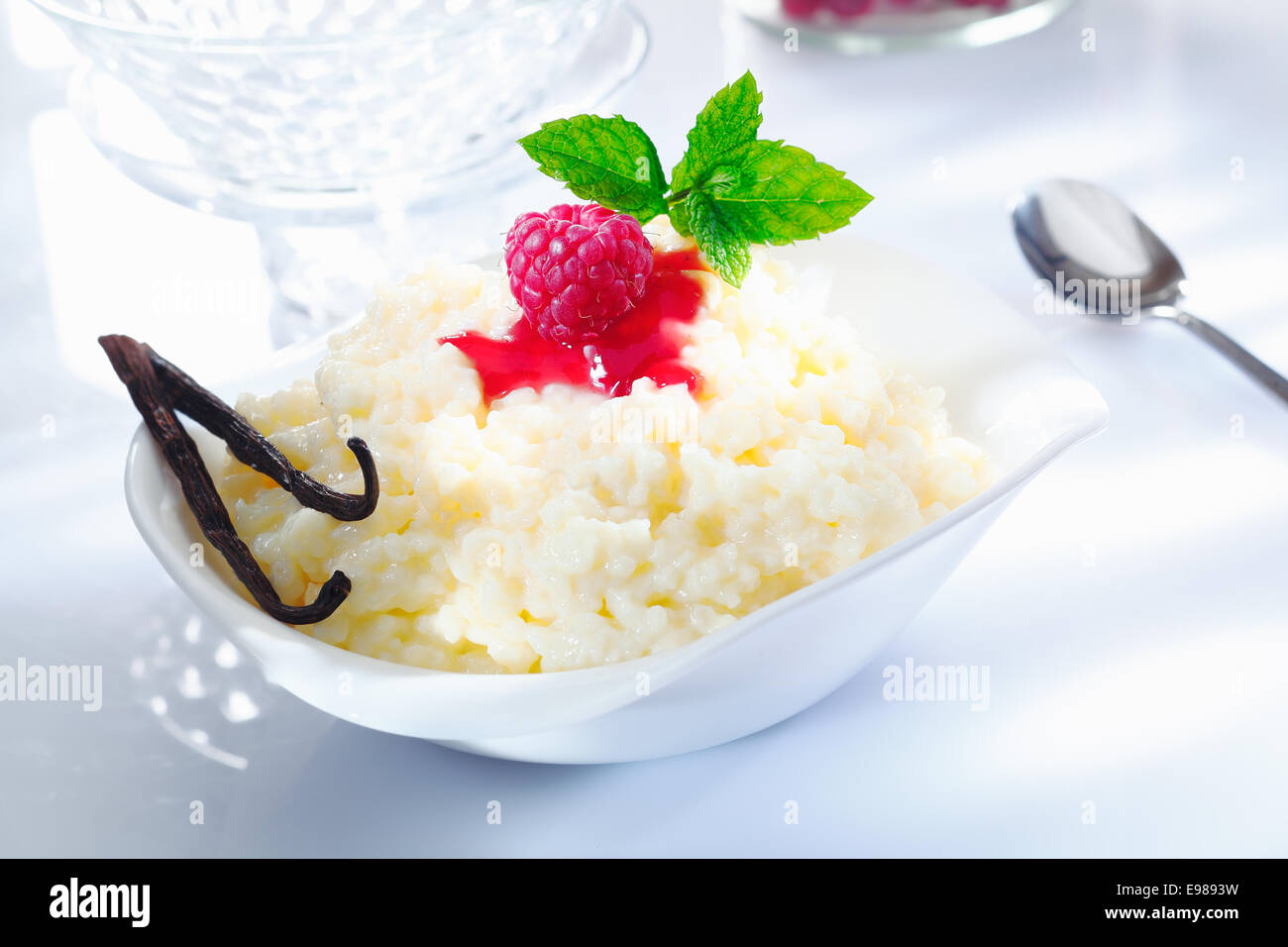 Fruttato budino di riso dolce con lampone topping e baccelli di vaniglia su sfondo bianco. Foto Stock