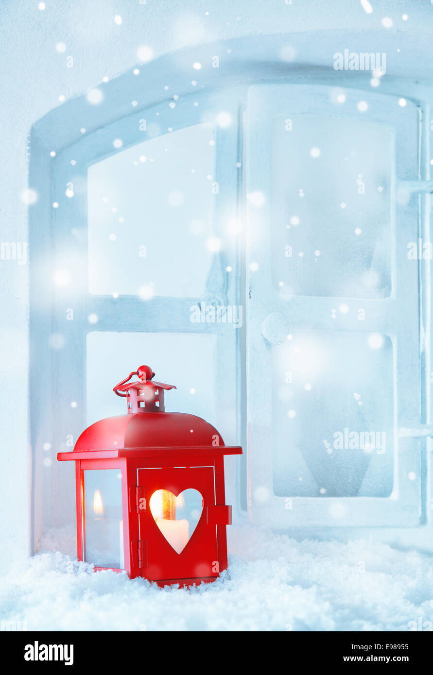 Rosso lanterna di natale luce di guida con un incandescente candela che brucia sul davanzale nella caduta di neve con copyspace per i vostri auguri stagionali Foto Stock Rosso lanterna di natale luce di guida con un incandescente candela che brucia sul davanzale nella caduta di neve con copyspace per i vostri auguri stagionali Foto Stock