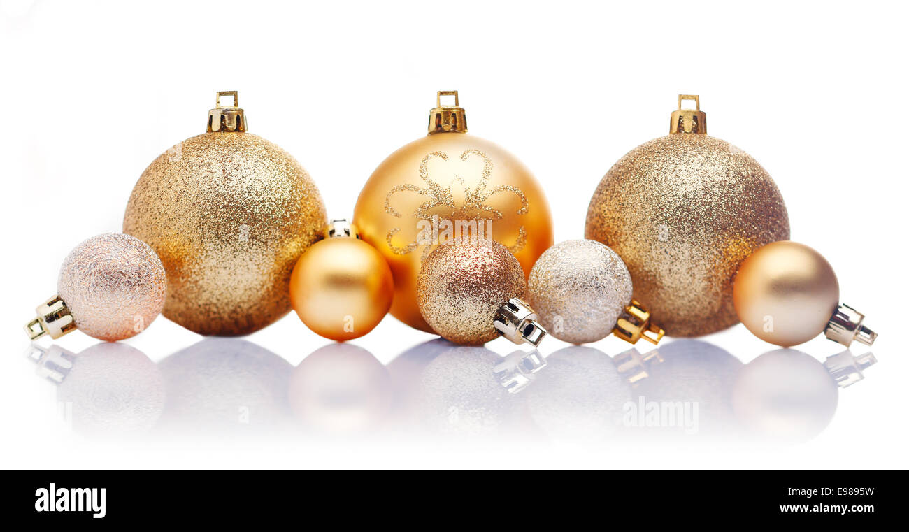 Una linea di grandi e piccoli in oro baubles di Natale con riflessioni contro uno sfondo bianco Foto Stock Una linea di grandi e piccoli in oro baubles di Natale con riflessioni contro uno sfondo bianco Foto Stock