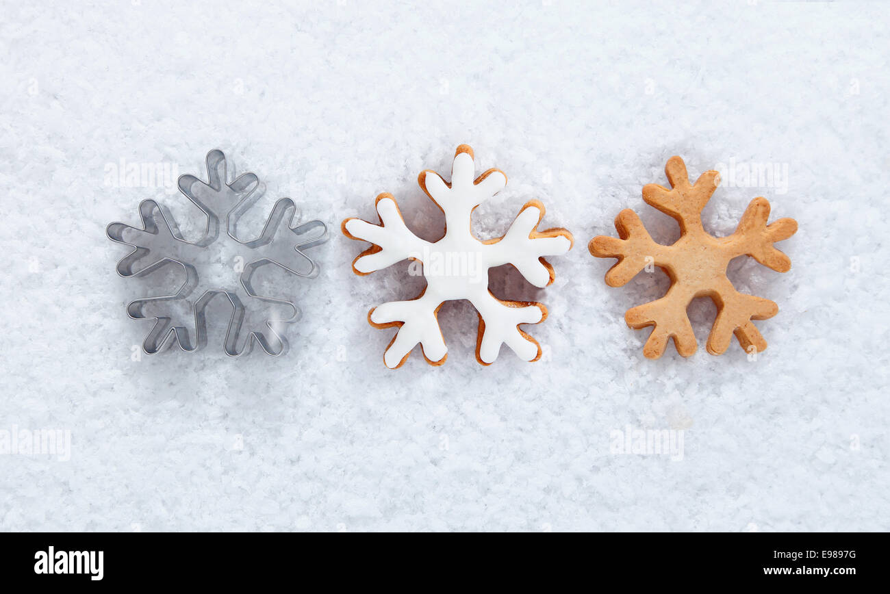 Inverno sfondo con tre diversi biscotti di fiocco di neve in fila su di un letto di neve fresca per un utilizzo in un tema di inverno o per i vostri auguri di Natale Foto Stock