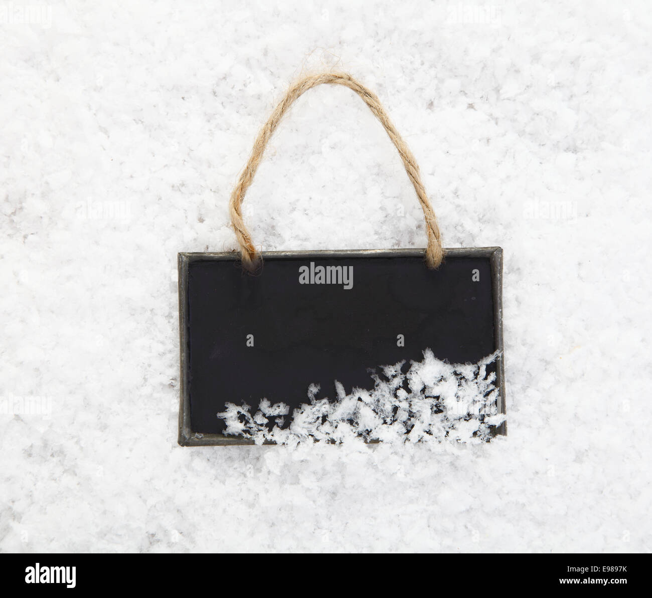 Un vuoto lavagna ardesia si accoccola in neve fresca pronta per il tuo tema invernale o messaggio di Natale Foto Stock