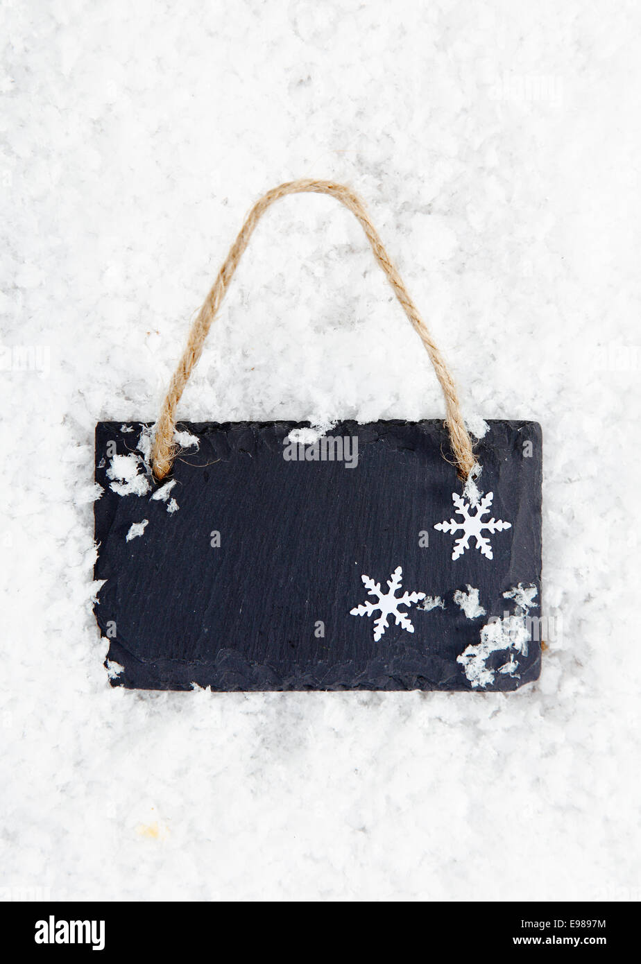 Vuoto lavagna in ardesia con copyspace per il tuo testo o messaggio sulla neve con i fiocchi di neve Foto Stock