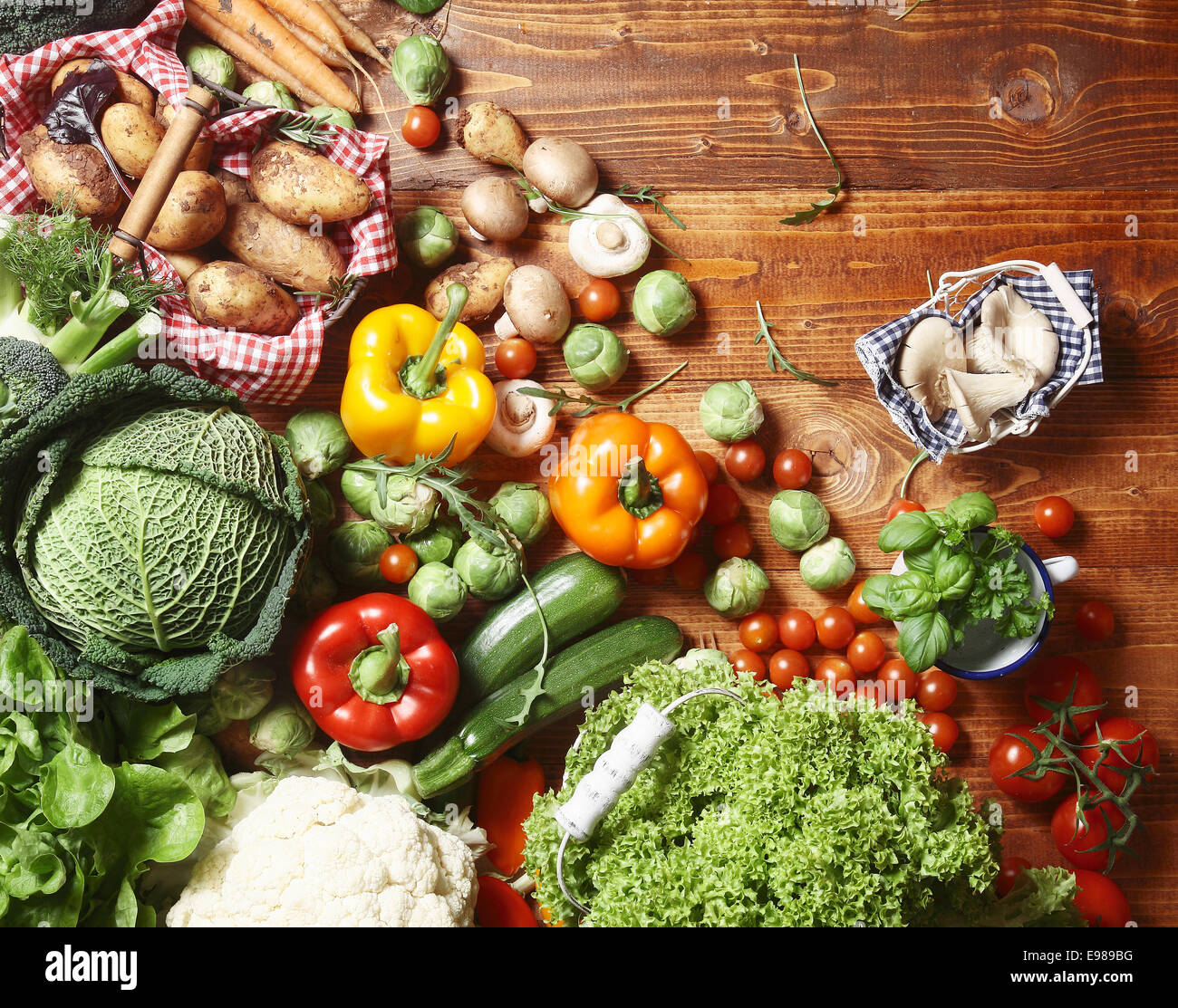 Vista aerea di un delizioso assortimento di fattoria fresco verdure, erbe e funghi distesa su una tavola in legno rustico Foto Stock