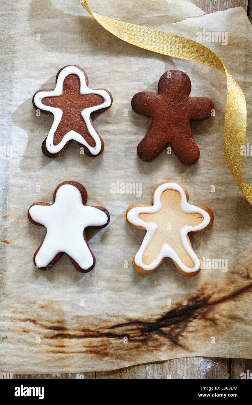 4 pan di zenzero uomini su un grunge carta da forno per il pranzo di natale e il concetto di cookie Foto Stock