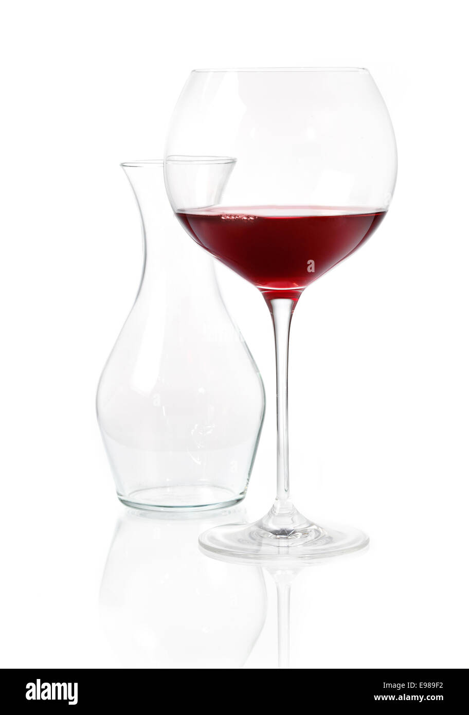 Bicchiere di vino rosso con un bicchiere vuoto carafeon una superficie bianca riflettente Foto Stock