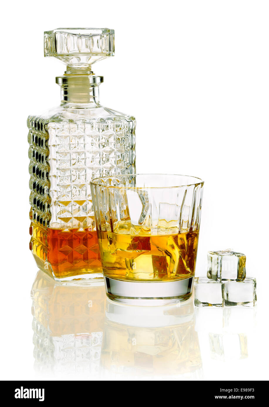 Whisky o brandy decanter con un bicchiere di whiskey su una superficie bianca riflettente Foto Stock