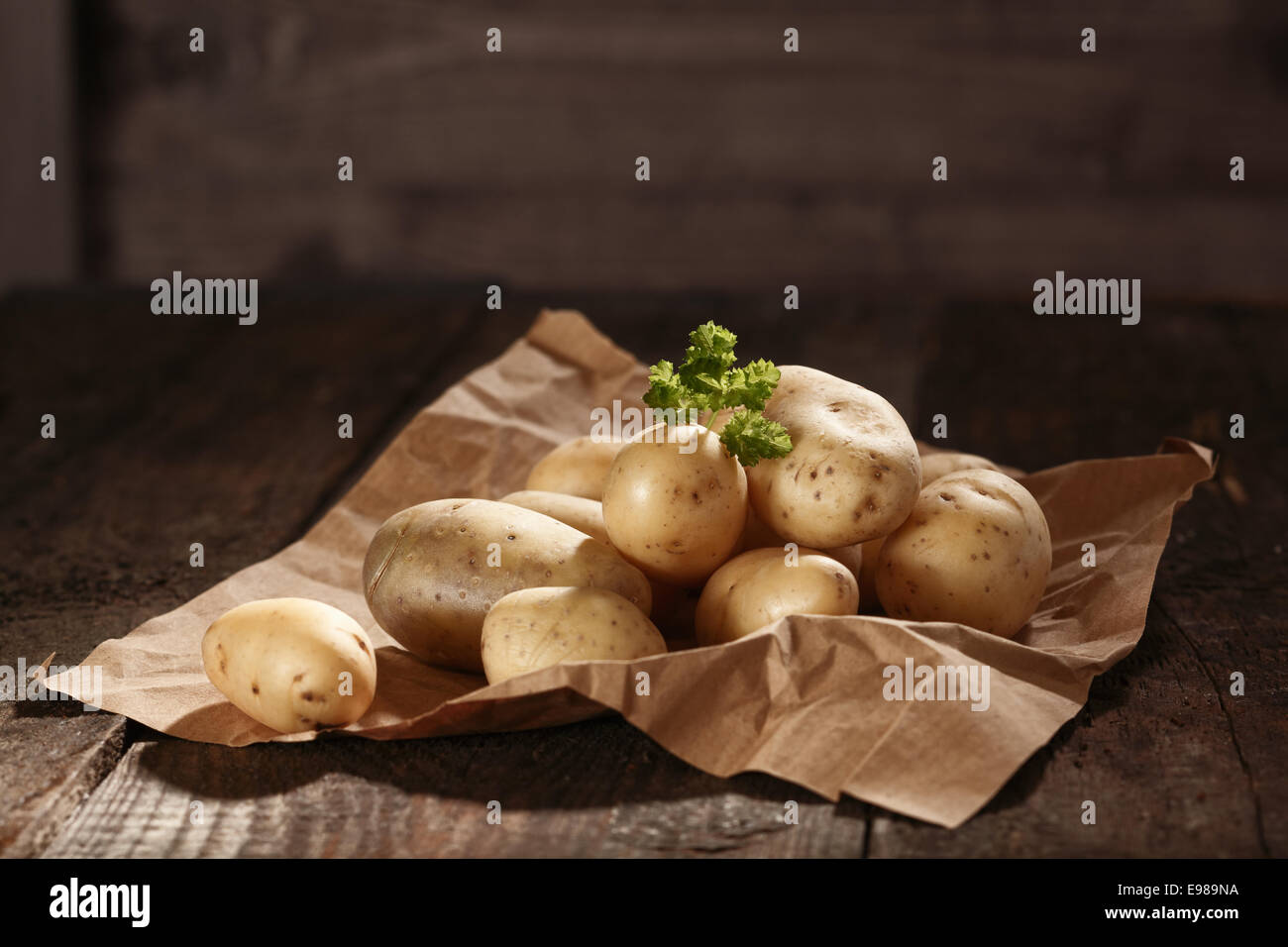 Pila di fresco e salutare intero crudo di patate su un foglio di accartocciata carta marrone con copyspace Foto Stock