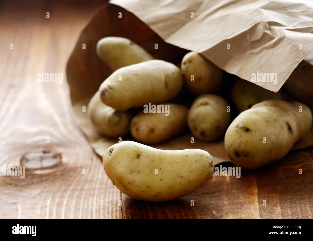 Azienda Agricola Patate fresche fuoriuscita di una carta marrone il pacchetto su una tavola in legno rustico sul mercato degli agricoltori Foto Stock