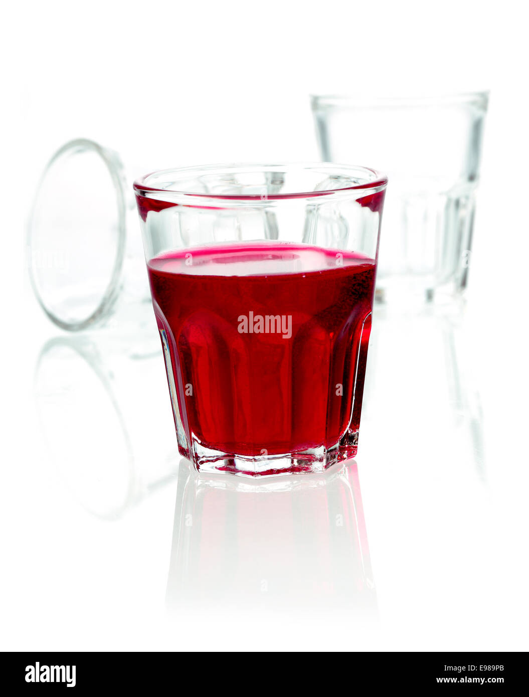 Bicchiere di red rum cocktail miscelato con succo di frutta e soda su un bianco di sfondo per studio con copyspace Foto Stock