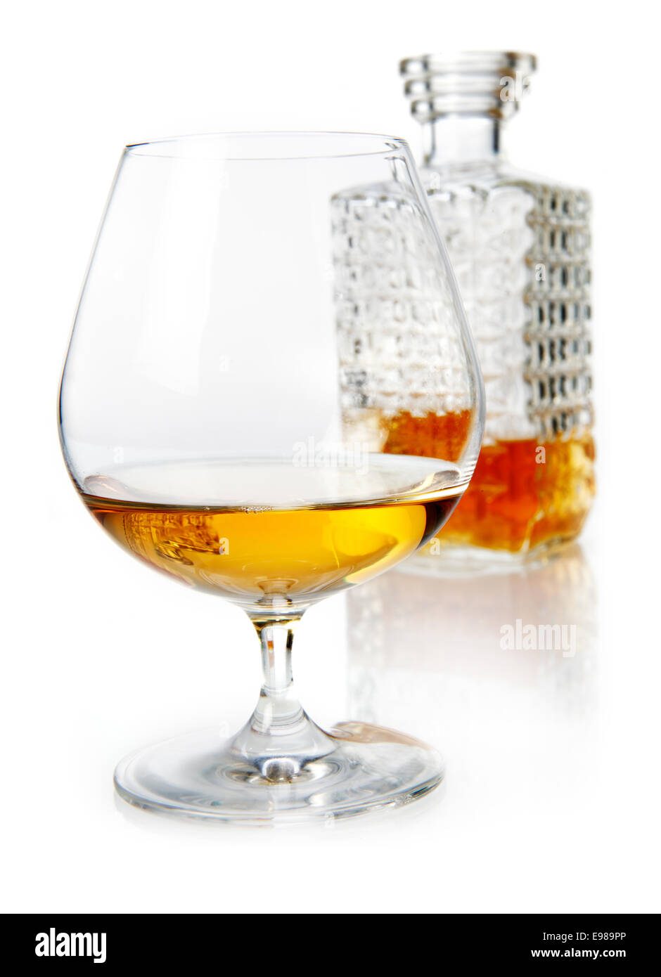 Età golden il brandy o il cognac in un snifter con un taglio decanter in vetro su un bianco riflettente di sfondo per studio Foto Stock