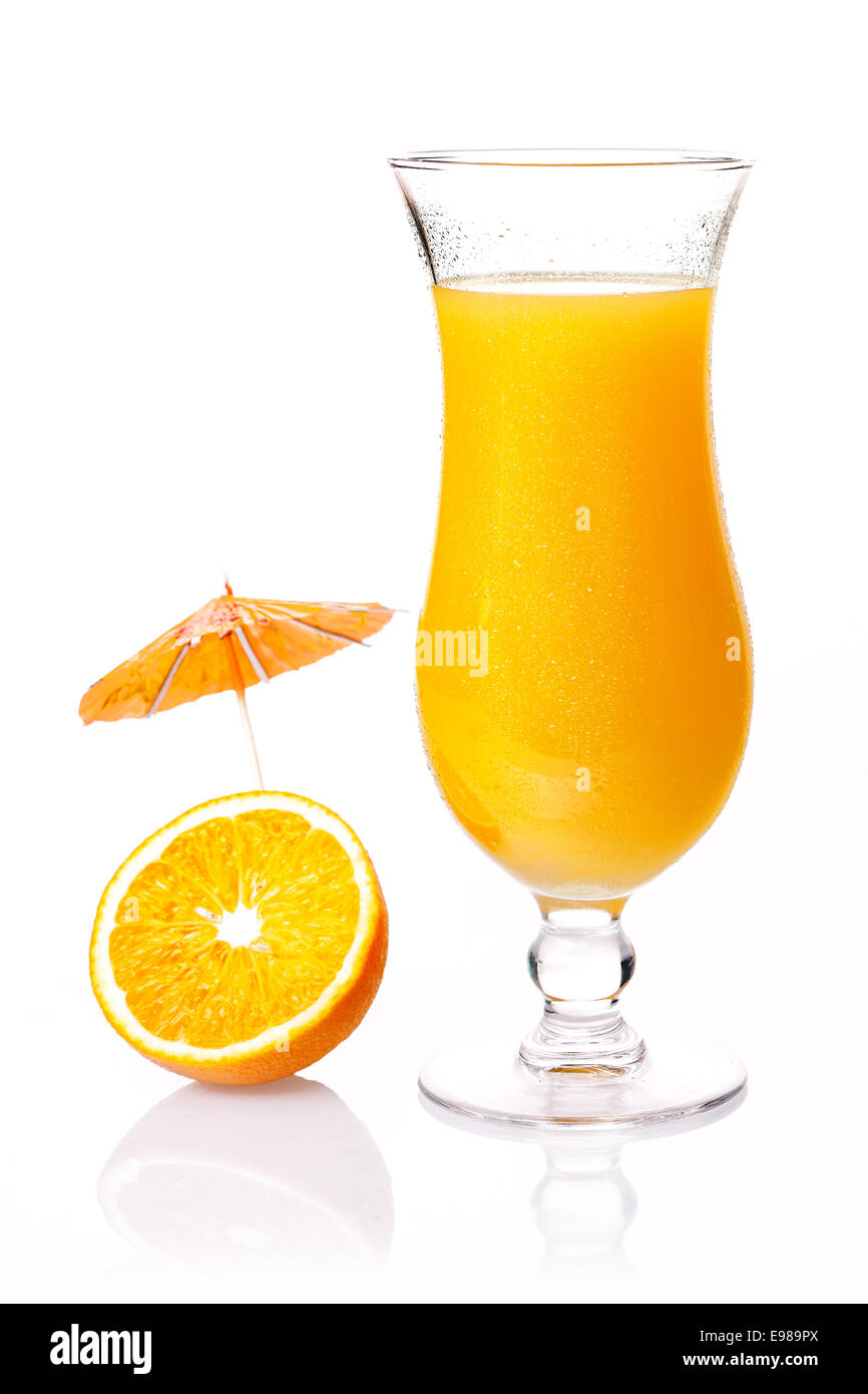 Bicchiere di fresco tropicale orange cocktail con un po' di cocktail party ombrellone su una metà del frutto su un bianco riflettente di sfondo per studio Foto Stock