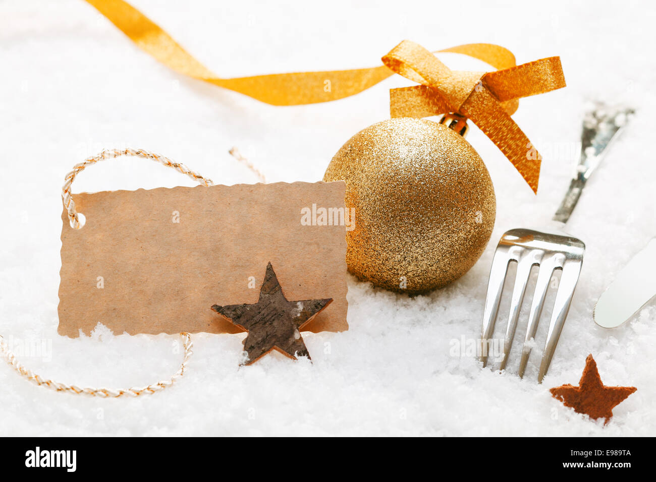 Luogo di festa impostazione con decorazioni di Natale e le posate d'argento in neve fresca con una decorazione blank gift tag Foto Stock