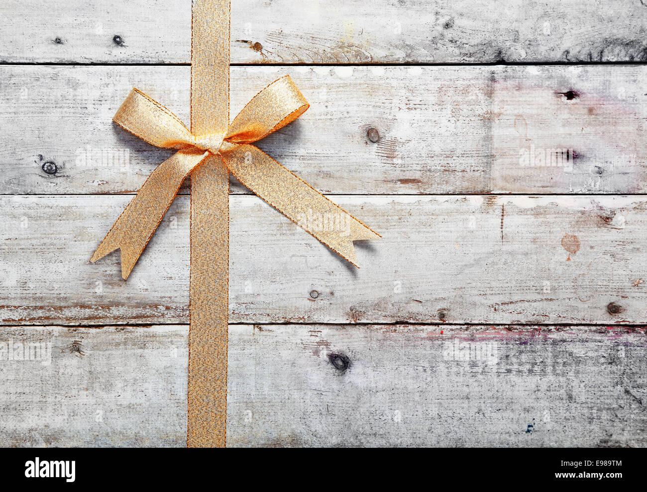 Golden decorativo di prua e di nastro sul vecchio rustiche tavole in legno con woodgrain copyspace per il tuo Natale, compleanno o anniversario messaggio Foto Stock