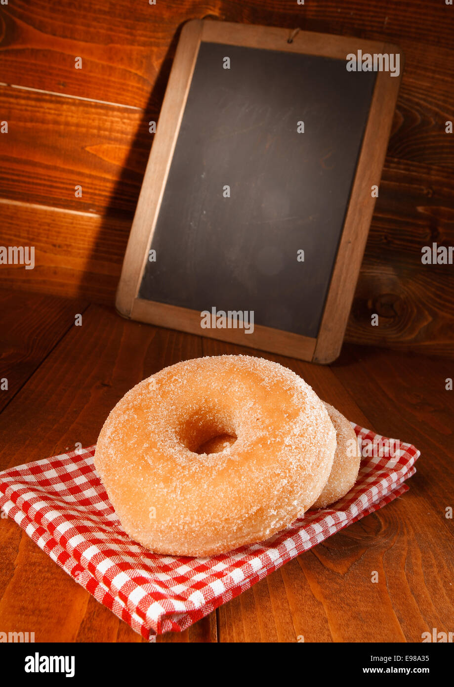 Una gustosa ciambella con lo zucchero vanigliato e un menu vuoto bordo dietro Foto Stock