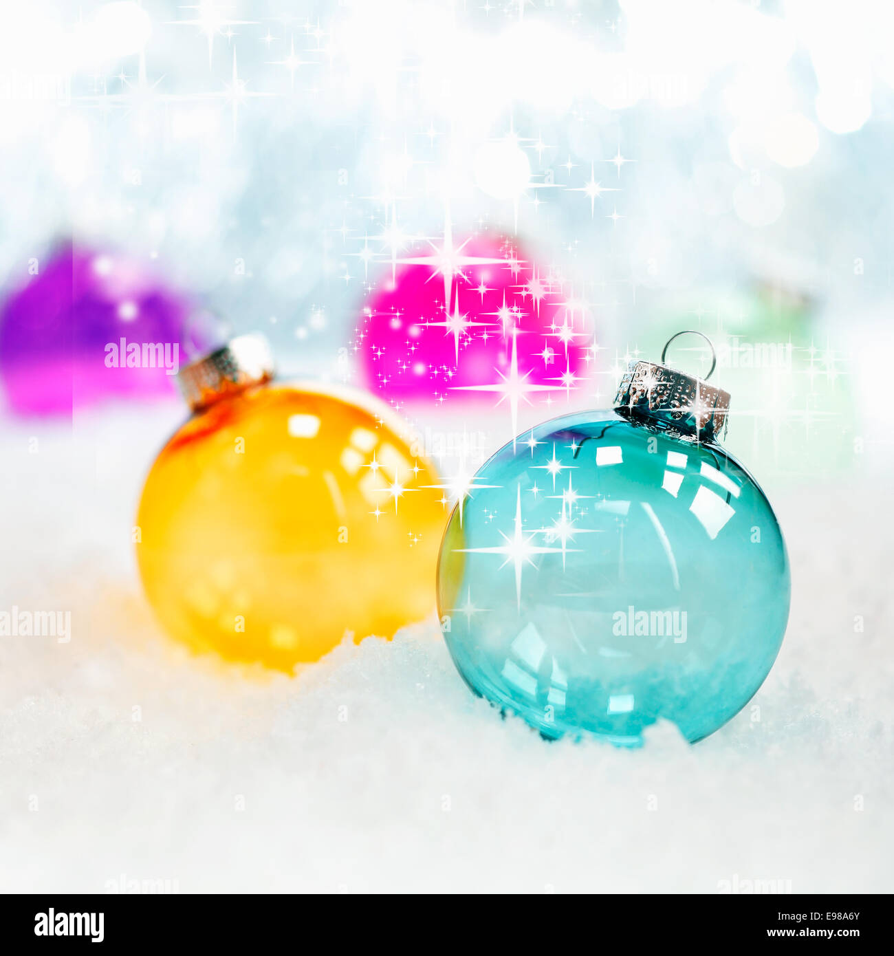 Vini spumanti batter colorate in vetro traslucido baubles di Natale nella neve fresca con bokeh di soft di luci bianche, formato quadrato Foto Stock