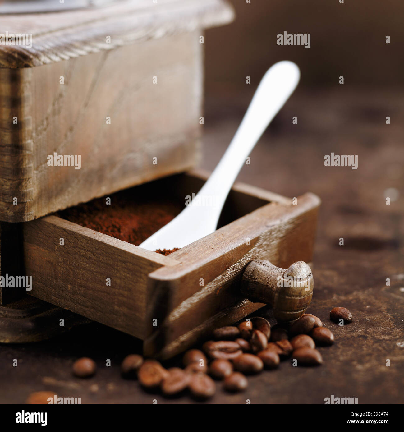 Caffè appena macinato e un cucchiaino dosatore in aprire il cassetto di un vecchio retrò macinino in legno Foto Stock